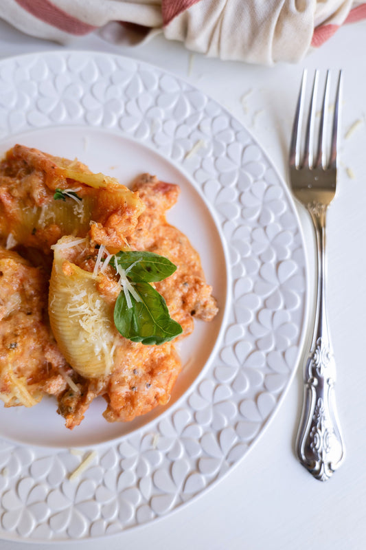Baked Italian sausage stuffed pasta shells on a decorative plate with fresh basil garnish