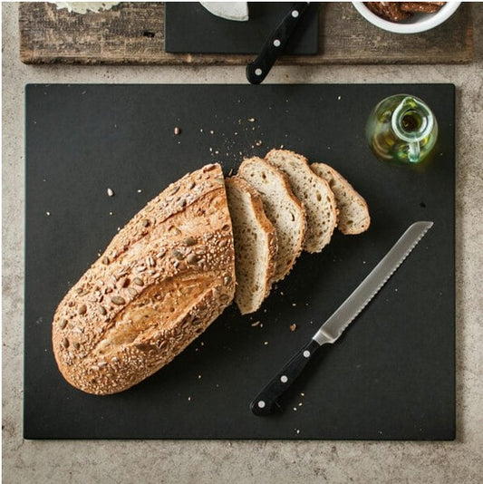 Sliced loaf of bread on a cutting board with a knife and olive oil bottle