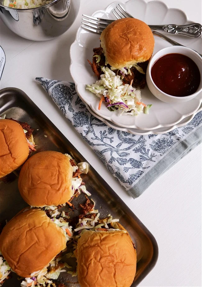 Burger sliders on a tray with a side of coleslaw and ketchup.