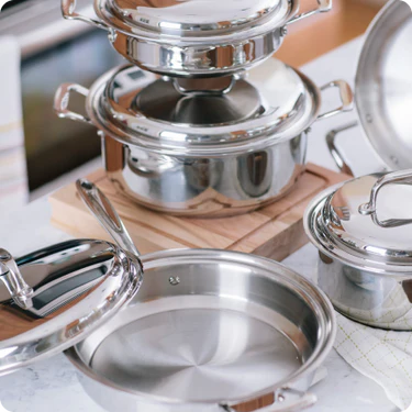 Set of stainless steel cookware on a wooden surface