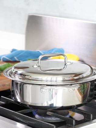 A stainless steel pot on a stove, demonstrating waterless cooking techniques.