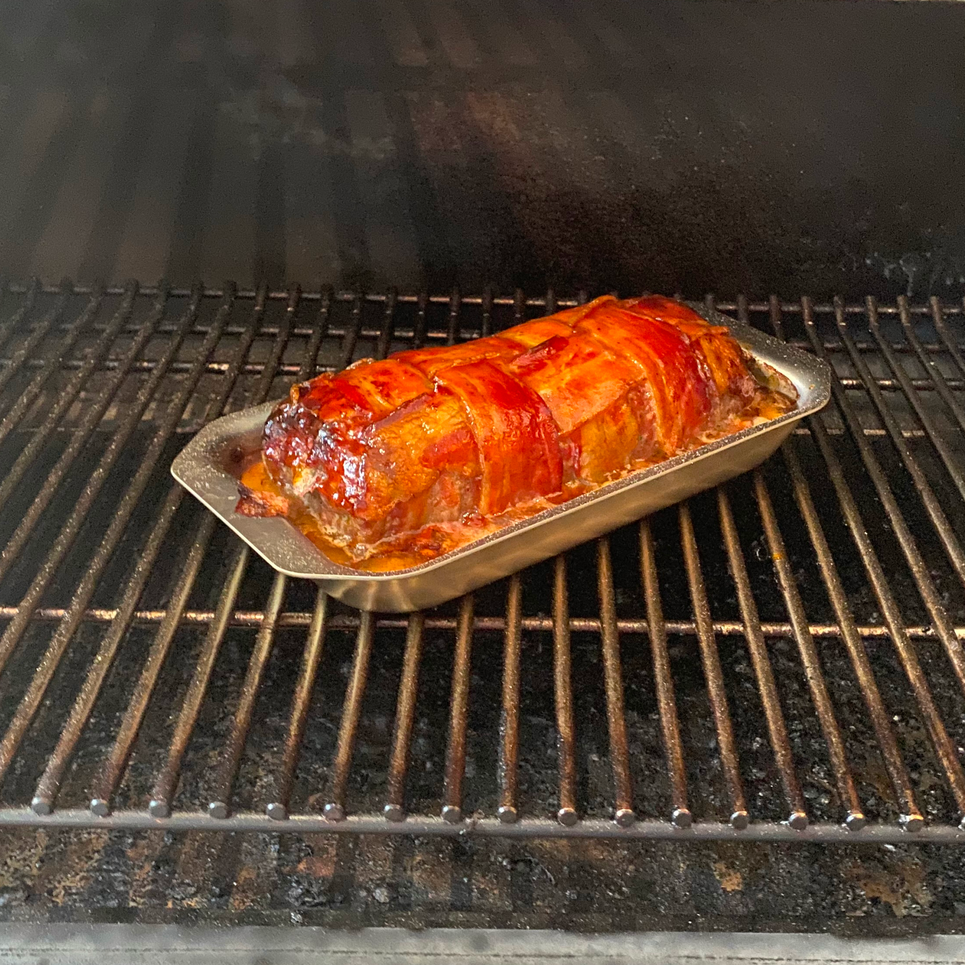A cooked meatloaf in a stainless steel mini jelly roll pan inside an oven.