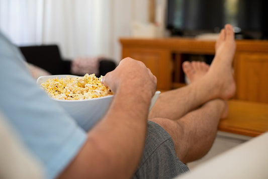 Person relaxing with a white salad bowl filled with popcorn