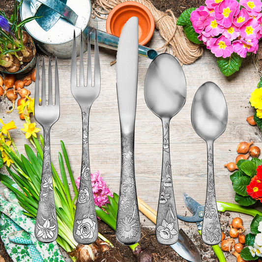 Five pieces of American Garden flatware with floral designs on handles, surrounded by gardening tools and flowers.