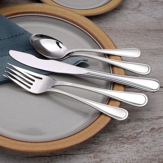 Four pieces of Classic Rim flatware on a plate, including a spoon, knife, and fork.