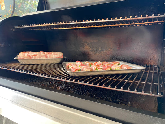 Two stainless steel pans with food cooking on a grill, showcasing the 360 Grilling Set.