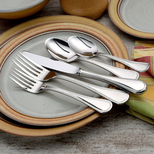 Set of stainless steel utensils including forks, knives, and spoons on plates