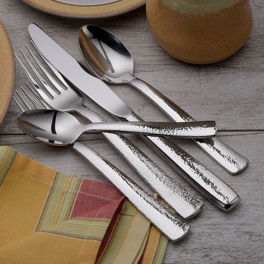 Pinehurst 45 Piece Set flatware displayed on a table with plates and a napkin