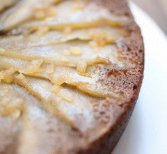 Close-up of stovetop gingerbread cake showcasing candied ginger slices and a light glaze on a white plate