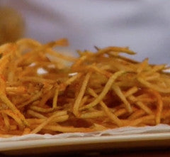 Close-up of pick-up-sticks style potato fries showcasing thin julienned golden-brown sticks on a white plate