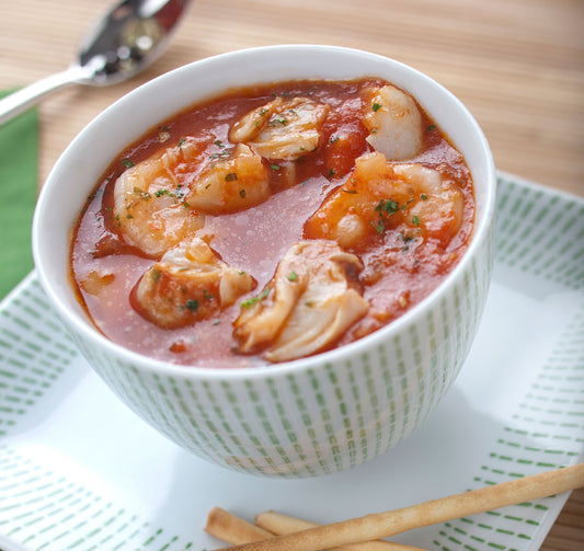 Bowl of seafood chowder with chunks of seafood and a garnish, served with breadsticks