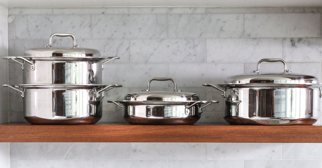 Three pieces of stainless steel 360 Cookware on a wooden shelf, showcasing their design and quality.
