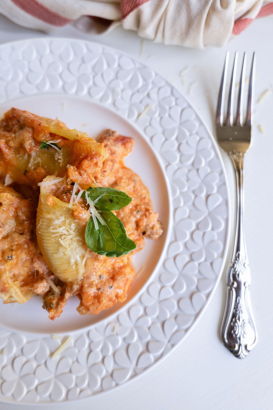 Baked Italian sausage stuffed pasta shells on a decorative plate with fresh basil garnish