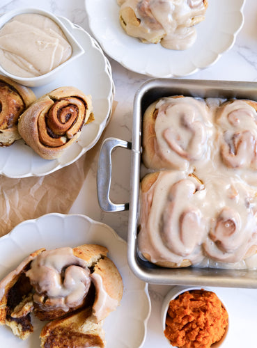Freshly baked cinnamon rolls topped with cream cheese icing, served with pumpkin puree and icing on the side.