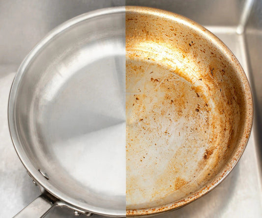 Top view of stainless steel pan showing left half polished clean and right half with burnt brown baked-on stains in a sink
