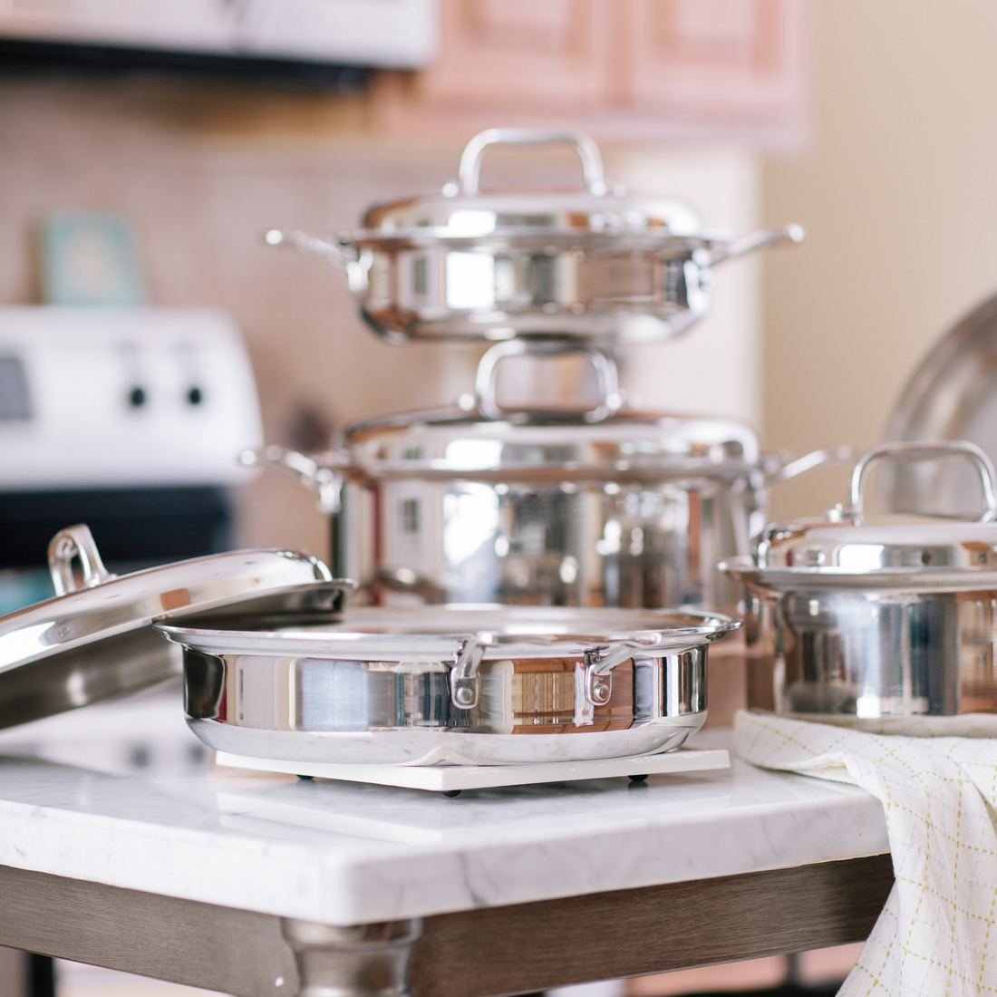 A stainless steel cookware set displayed on a kitchen countertop, including various pots and lids.