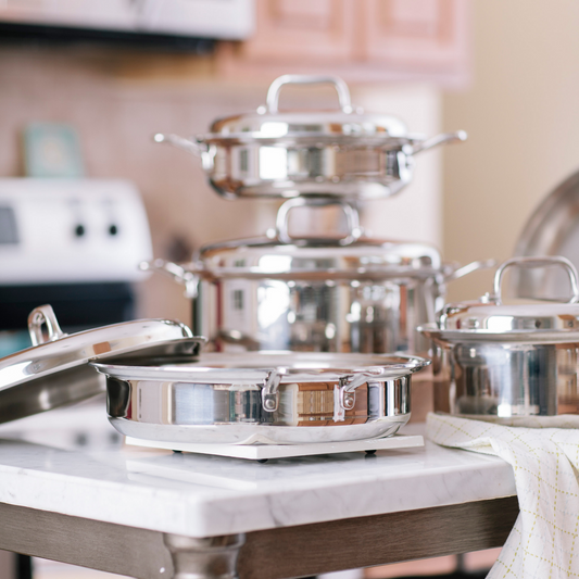 A stainless steel cookware set displayed on a kitchen countertop, including various pots and lids.