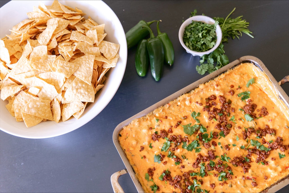 Baked chorizo queso dip in a rectangular pan with tortilla chips, jalapeños and cilantro