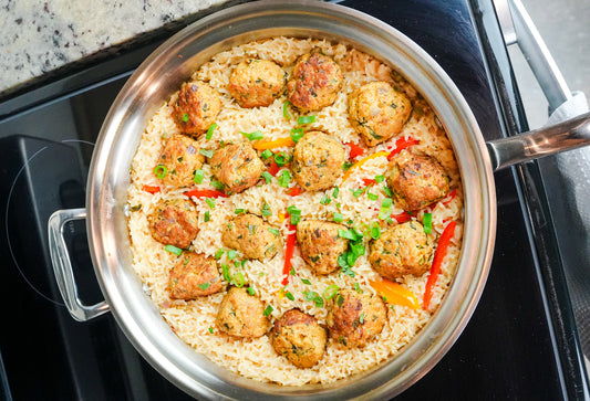 One-pan cilantro chicken meatballs on coconut rice in a stainless steel pot on a stovetop