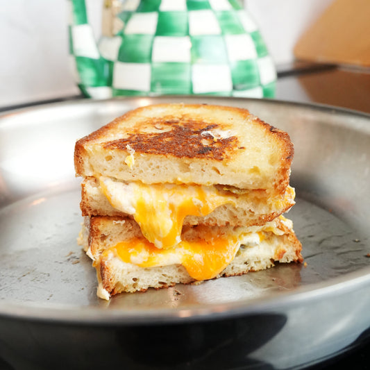 Close-up of stacked jalapeno popper grilled cheese showing gooey melted cheese and crispy toasted bread on a metal pan
