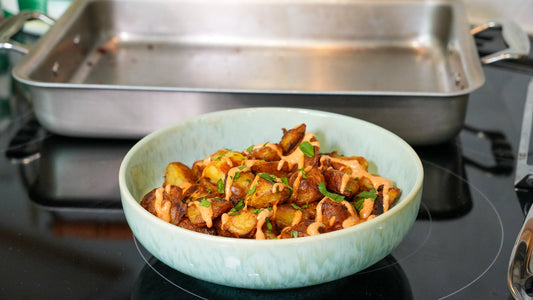 Close-up of patatas bravas showcasing crispy roasted potatoes drizzled with sauce and garnished with parsley