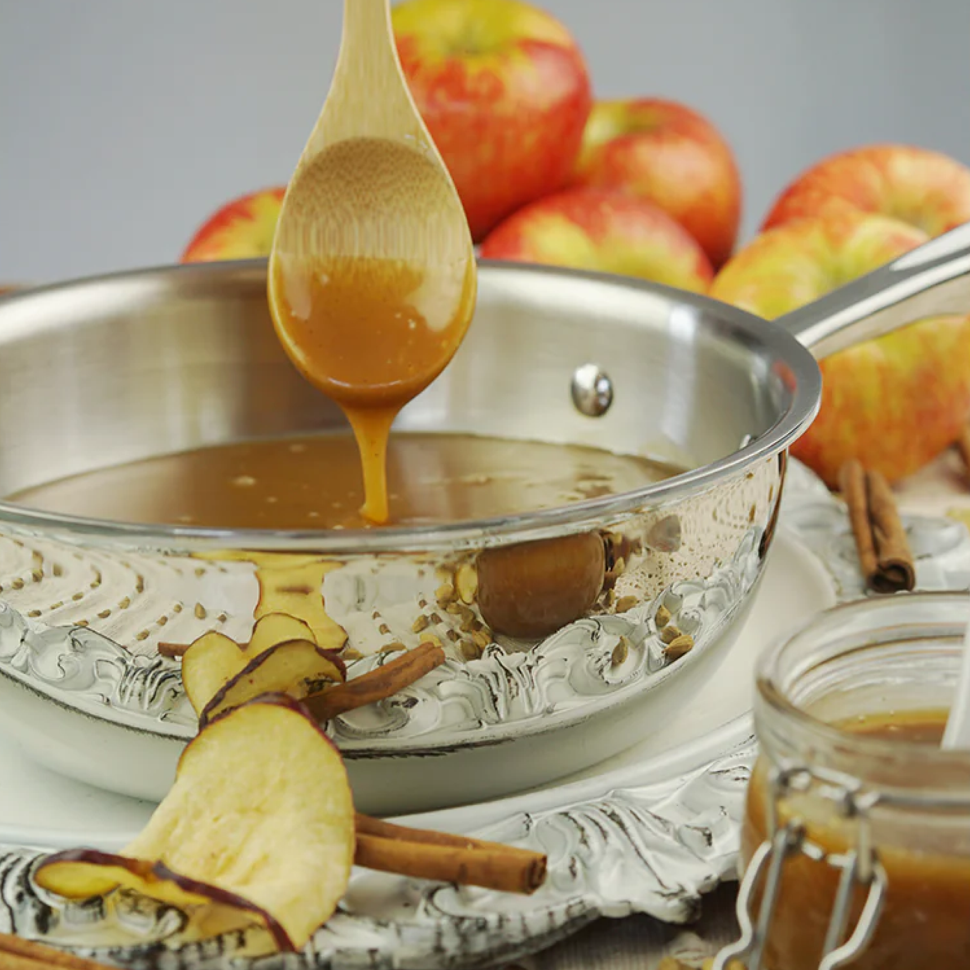 A 2 Quart Saucier with caramel sauce and apples, surrounded by cinnamon sticks and dried apple slices.