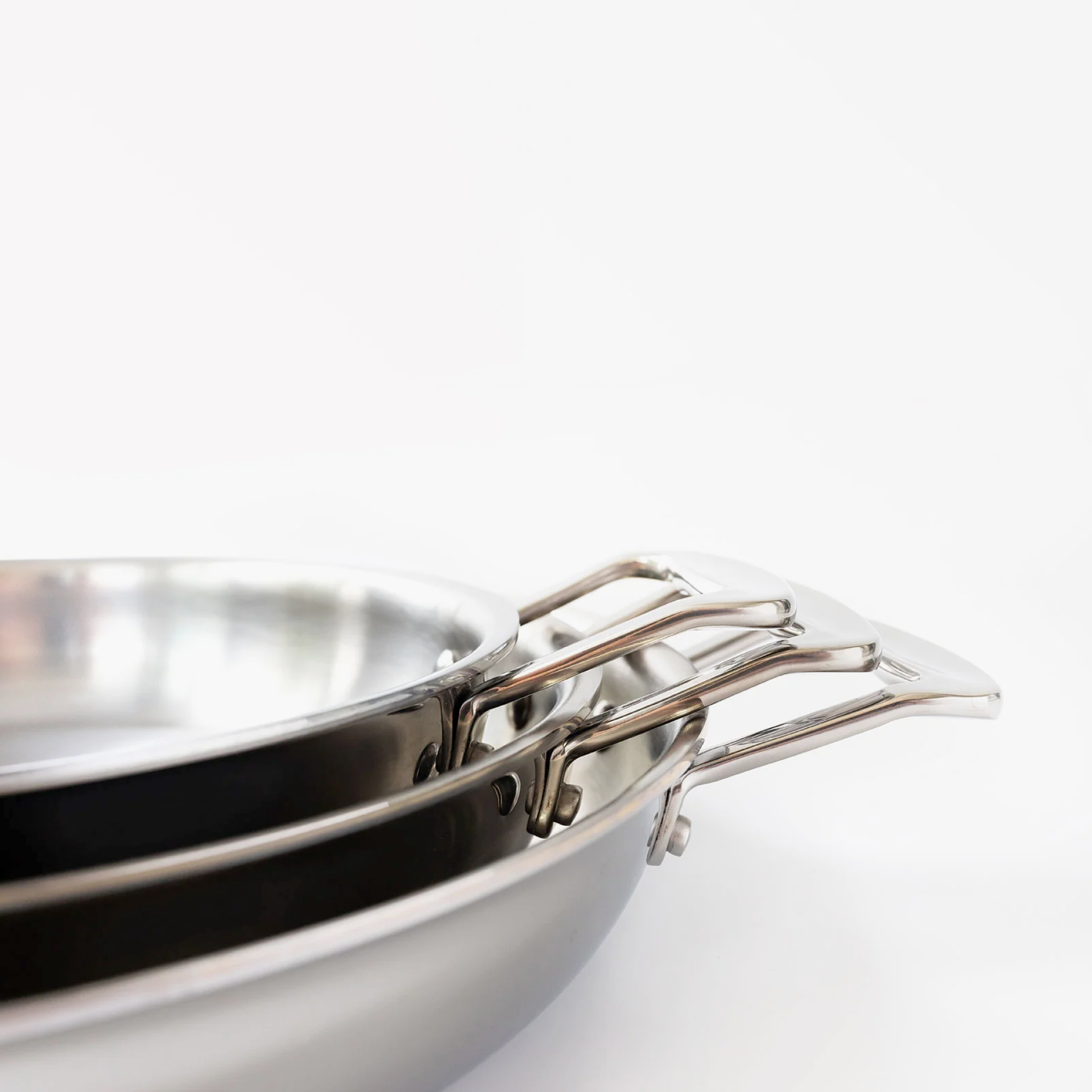 Three stackable short-handled fry pans showing surgical-grade stainless steel construction.