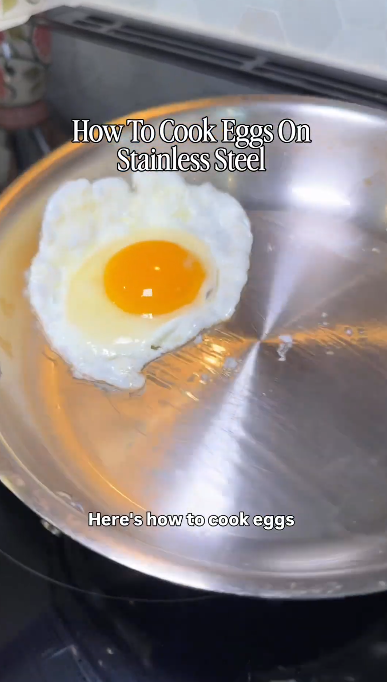 Fried egg cooking in a stainless steel pan with headline How to Cook Eggs on Stainless Steel