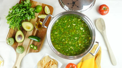Green soup in a pot with fresh ingredients on a wooden board