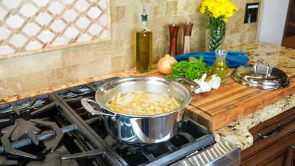Stovetop with a pot of food, cutting board with vegetables, and kitchen counter.