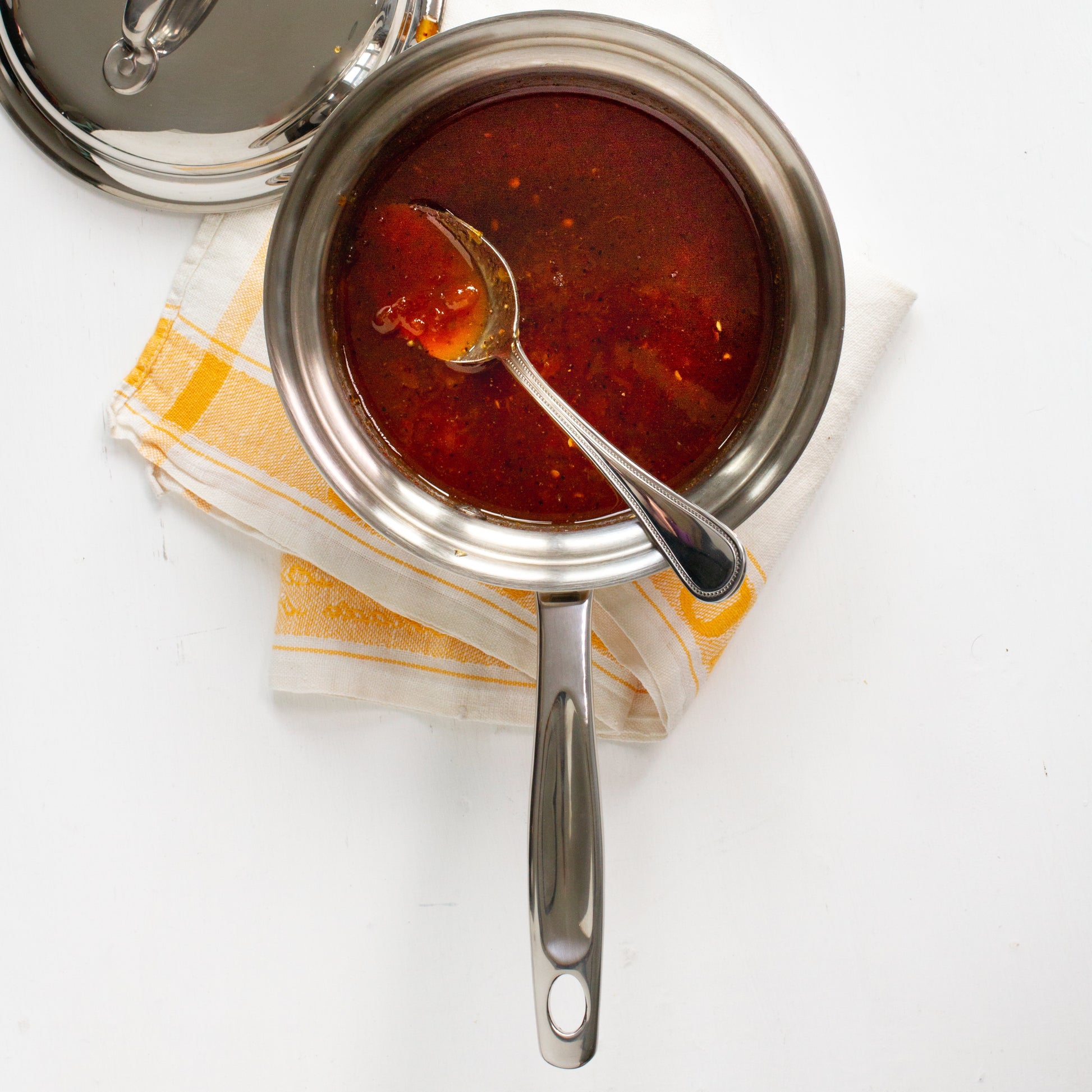 2 Quart Saucier with sauce and spoon on a towel