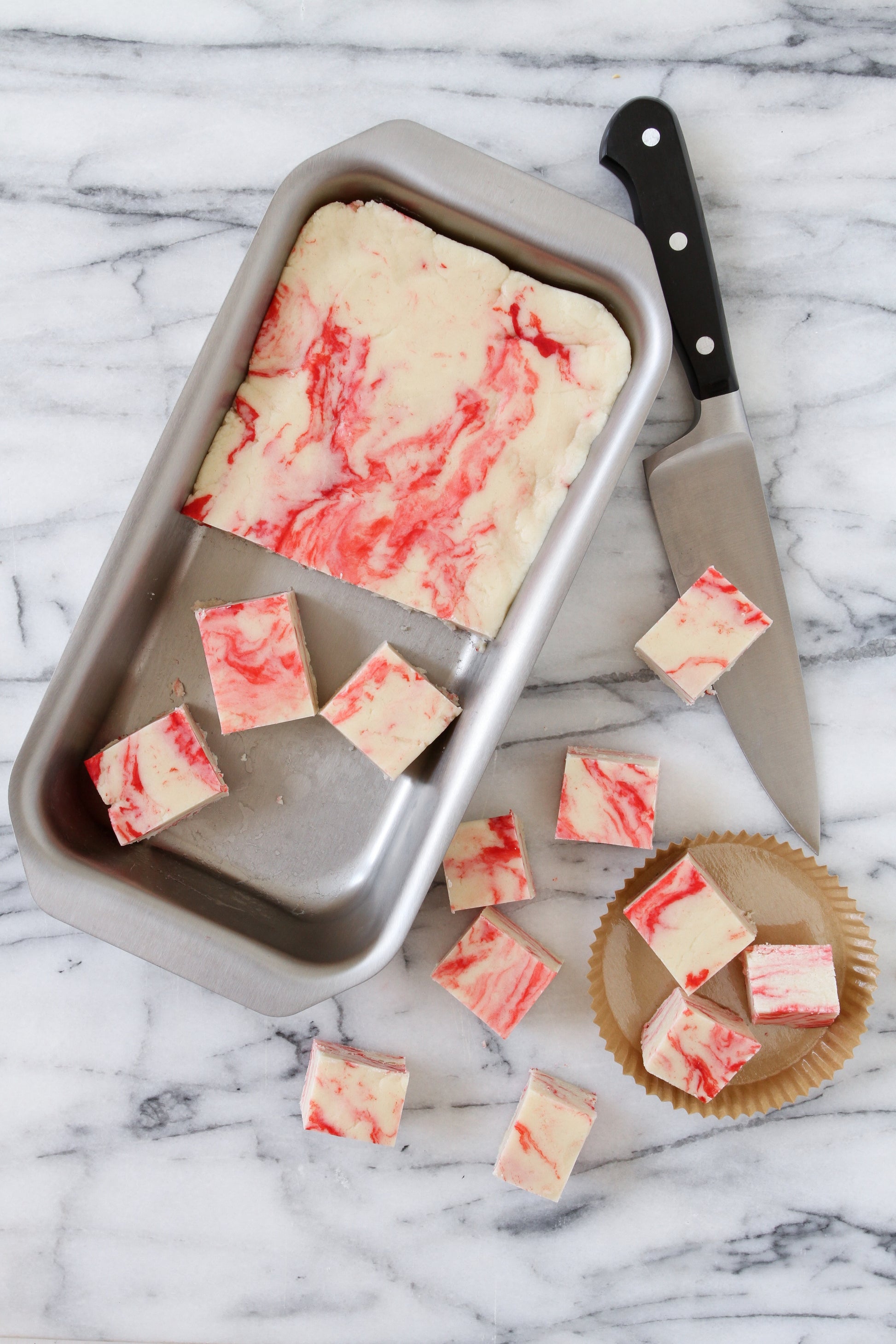 Marbled dessert in stainless steel bread pan with knife and cut pieces
