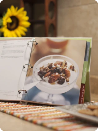 Open 360 Cookware cookbook showing a page with a photograph of a dish, sunflower in the background