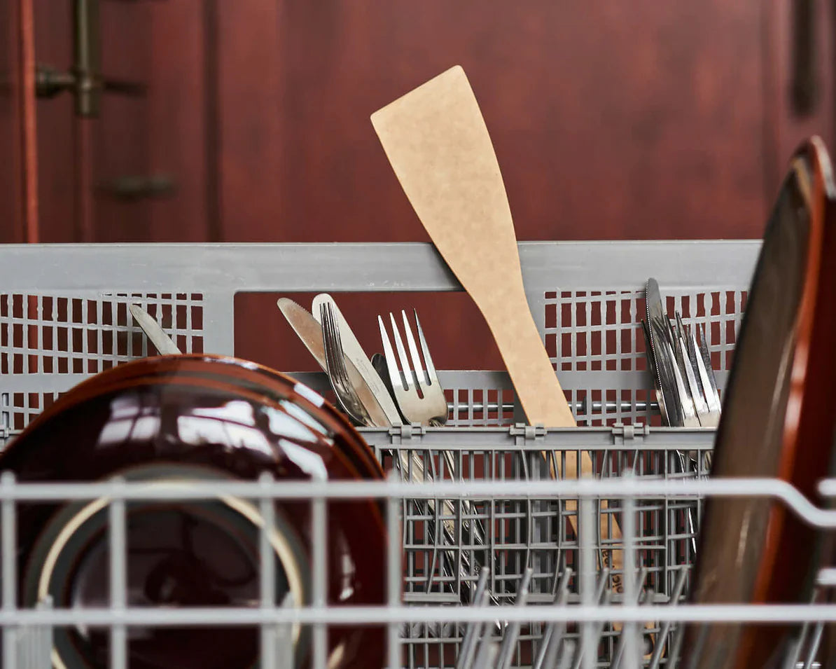 Kitchen utensils, including a spatula, in a dishwasher.