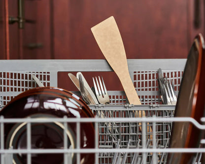 Kitchen utensils, including a spatula, in a dishwasher.