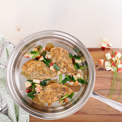 Sauté pan with seasoned chicken and chopped vegetables in a light broth.