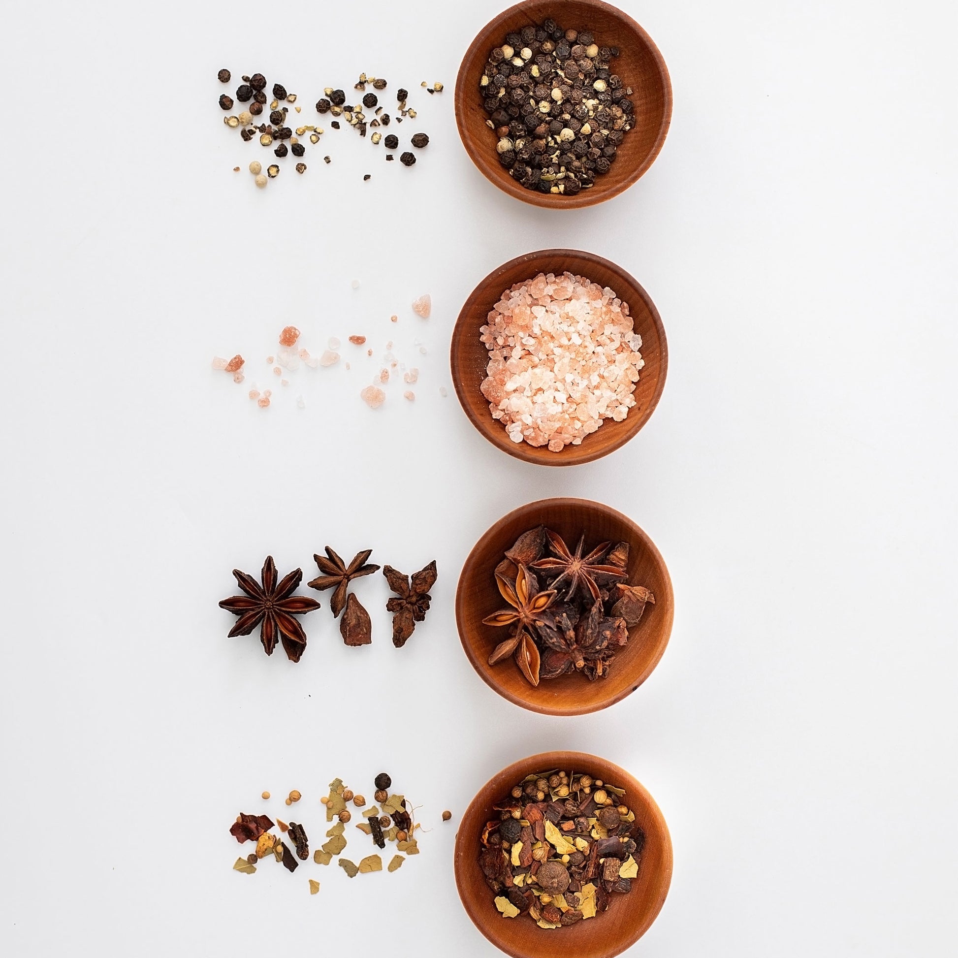 Four 2-inch maple condiment cups filled with various spices and salts arranged vertically.