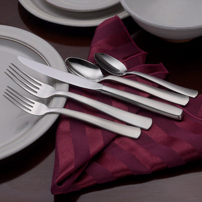 Satin America 65 Piece Set including forks, knives, and spoons on a table setting with plates and a napkin