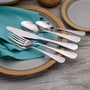 Angled view of Annapolis flatware pieces showing polished mirror finish on turquoise napkin and ceramic plate