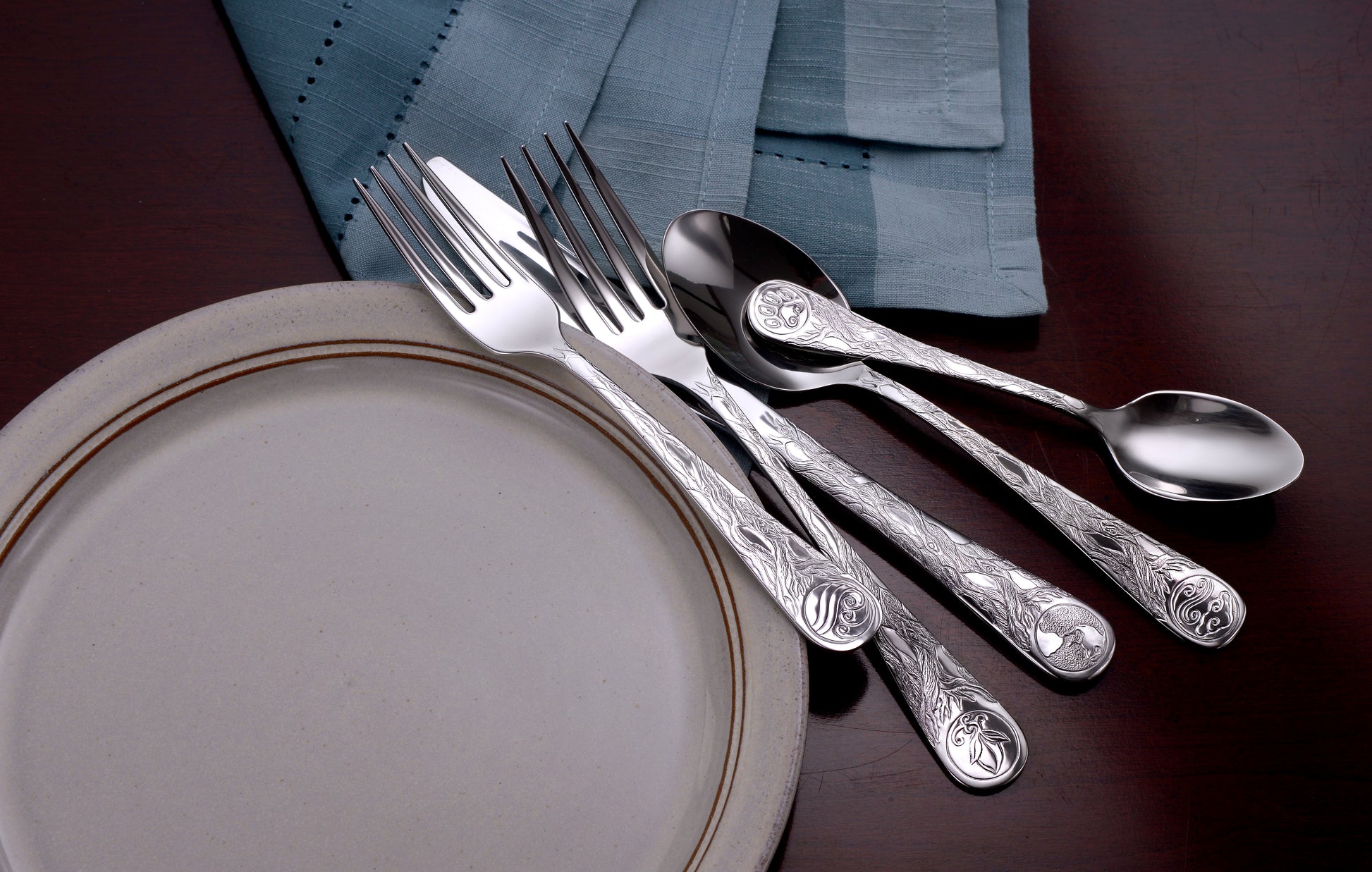Earth Pattern Flatware set displayed on a table with a plate and napkin.