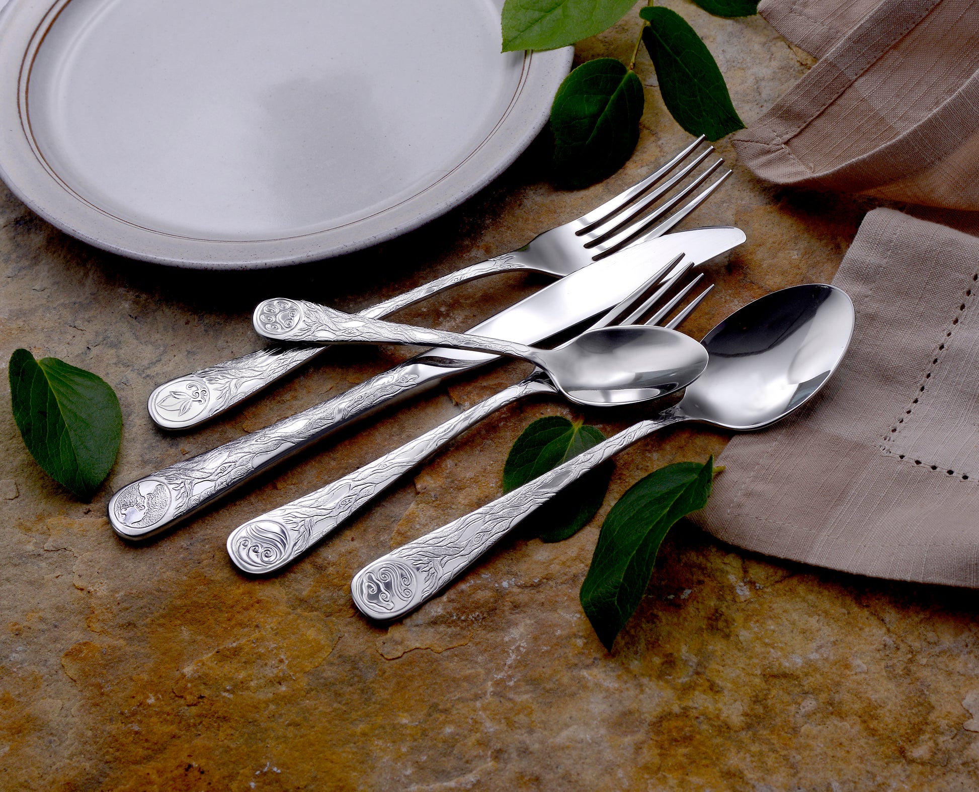 Earth Pattern Flatware set displayed on a table with leaves and a plate