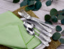 Top view of Earth flatware showing engraved handles on forks and spoons with green gingham napkin and eucalyptus
