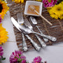 Angled view of Honey Bee 45-piece set flatware showing honeycomb bee-patterned handles on woven placemat with honey dipper