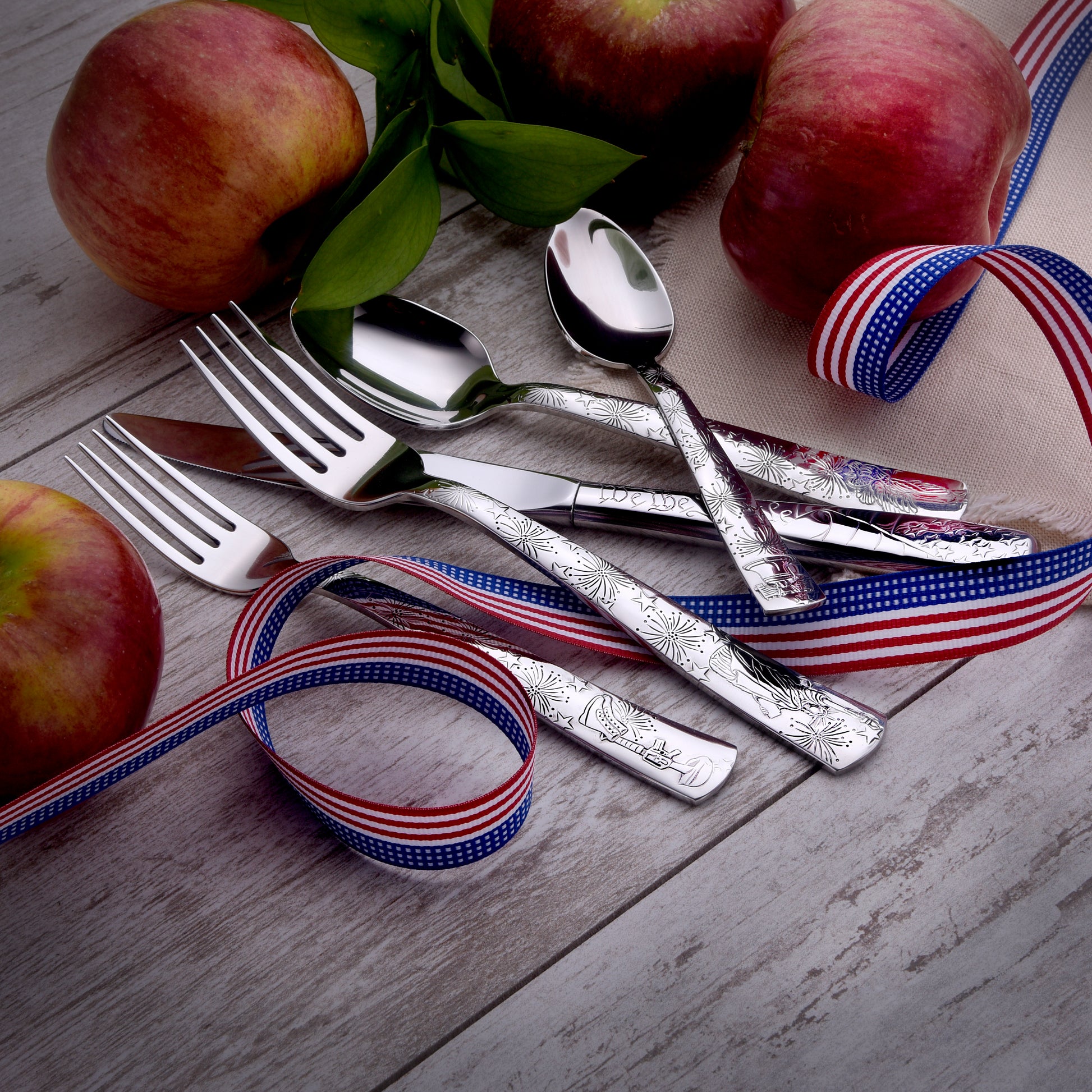 Cutlery set with apples and decorative ribbons on a wooden surface