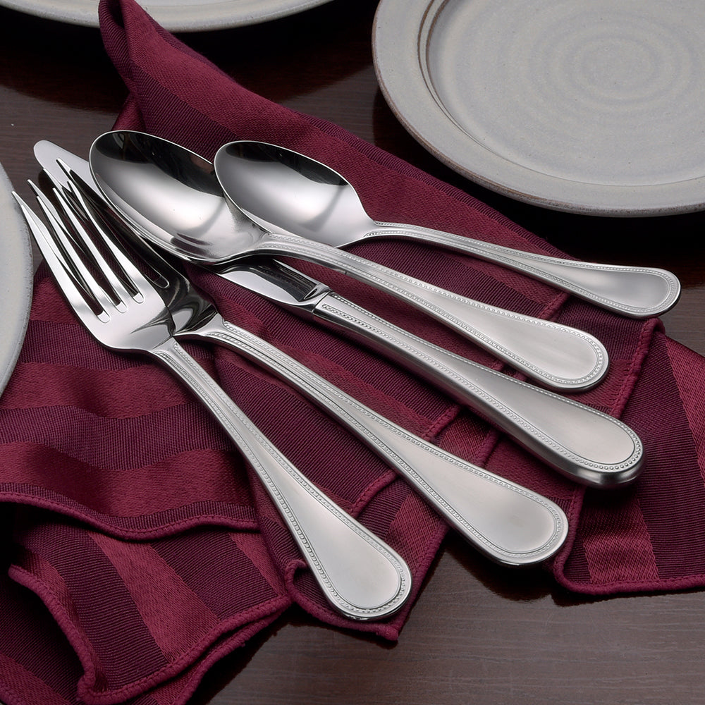 Satin Pearl 65 Piece Set displayed with forks, spoons, and knives on a maroon napkin and plates