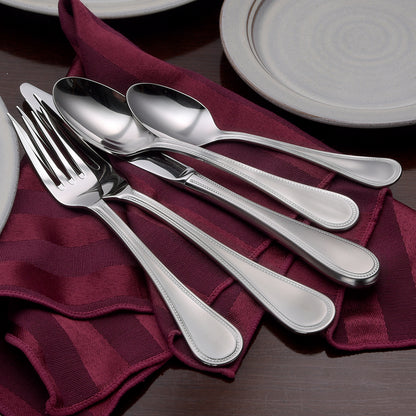 Satin Pearl 65 Piece Set displayed with forks, spoons, and knives on a maroon napkin and plates