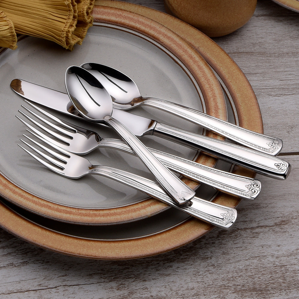 Five pieces of Prestige flatware on a plate, including a knife, spoon, and forks.