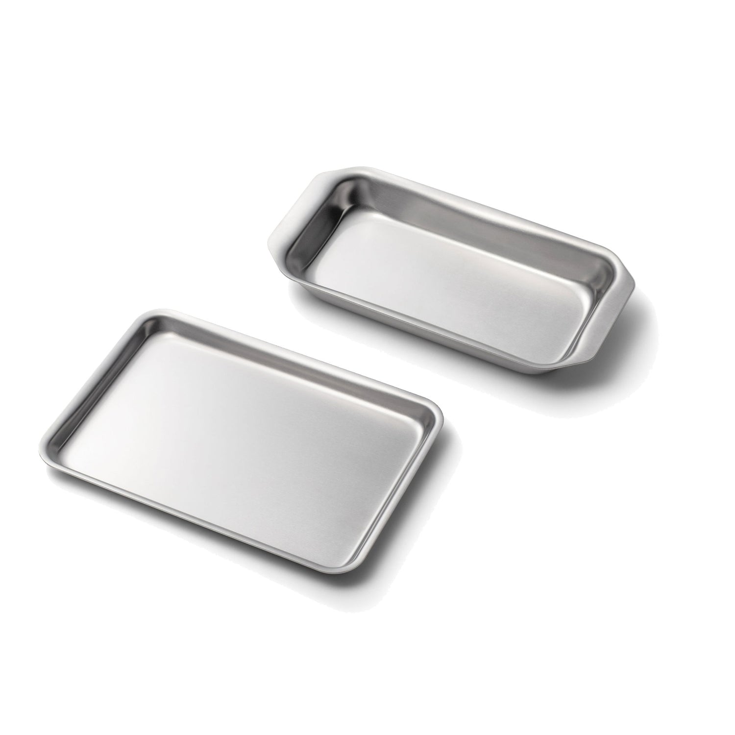 Angled view of two stainless steel mini loaf and jelly roll pans with rolled edges and smooth finish on white background